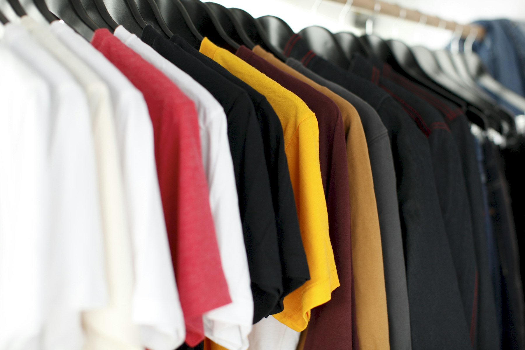 A rack of colorful t-shirts on hangers in a clothing store
